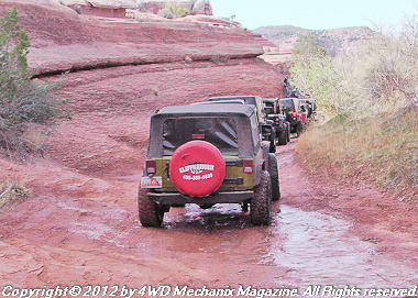 Jeep 4x4s at Moab, Utah, head up a sand canyon.