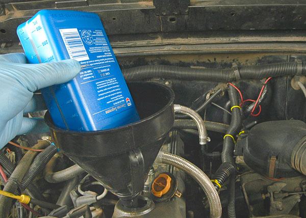 Using a funnel to fill the Jeep engine oil.